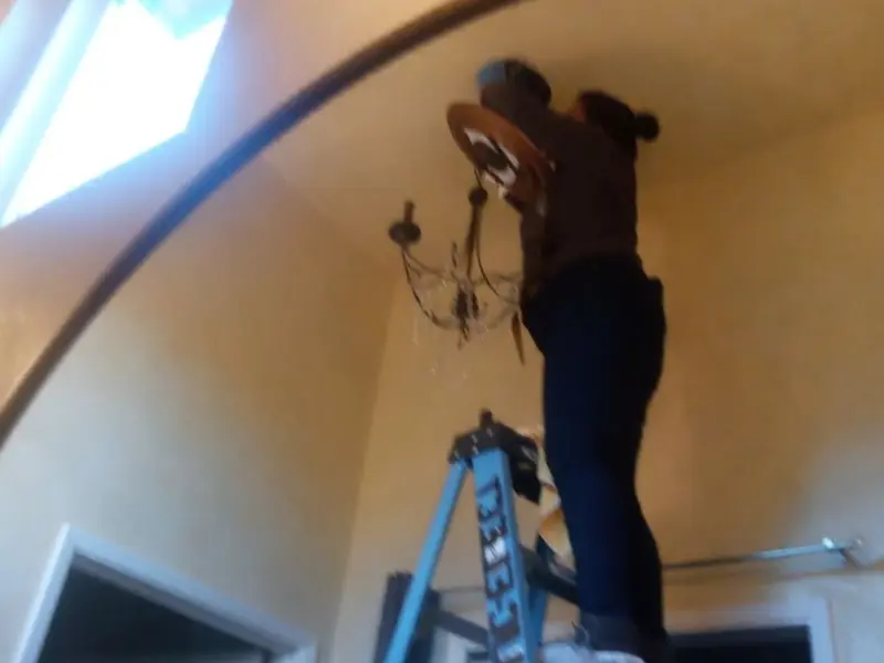 Electrician installing a chandelier in a Pontiac residence